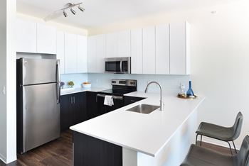 A modern kitchen with a white countertop and black cabinets.